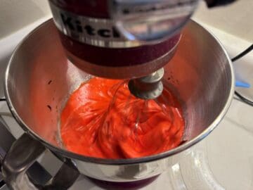 red meringue mixing in the bowl of a stand mixer