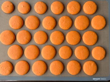a tray filled with orange nut free macaron shells