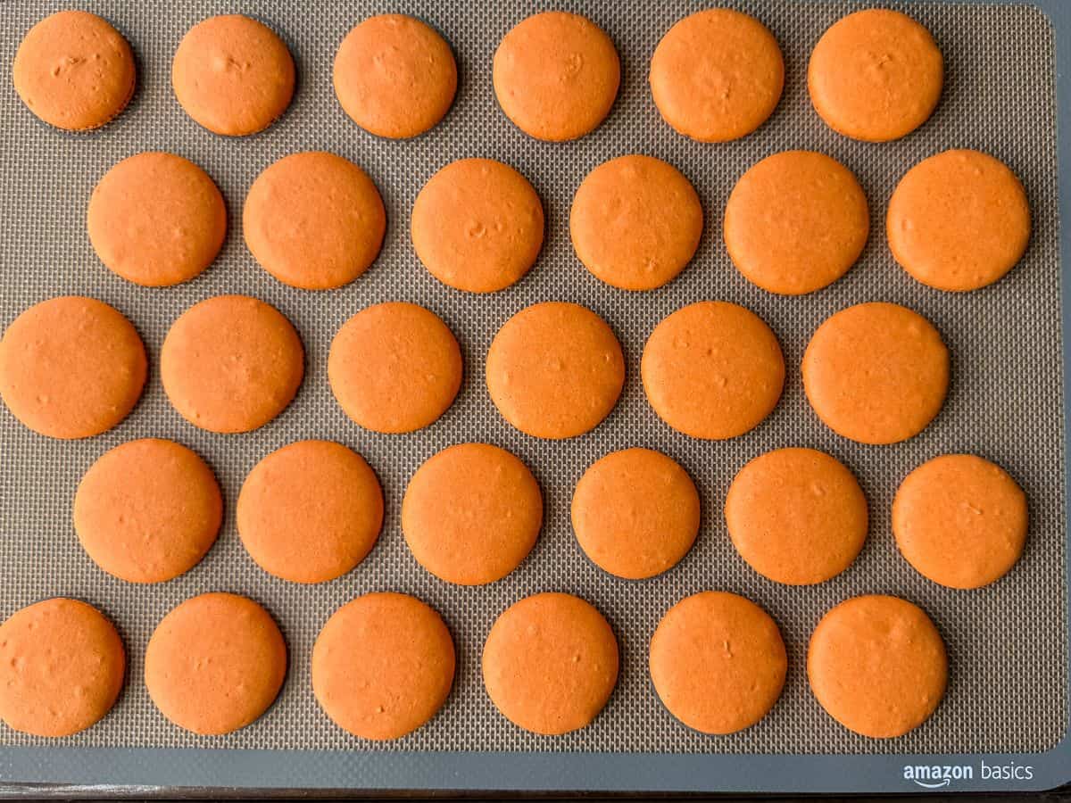 a tray filled with orange nut free macaron shells