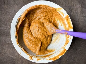 a bowl with spiced pumpkin filling and a purple small silicone spatula