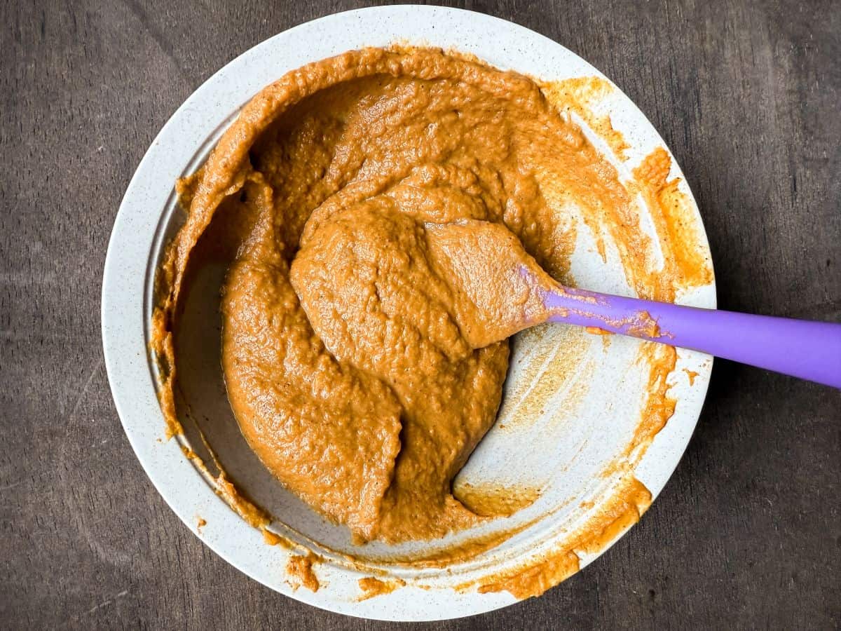 a bowl with spiced pumpkin filling and a purple small silicone spatula