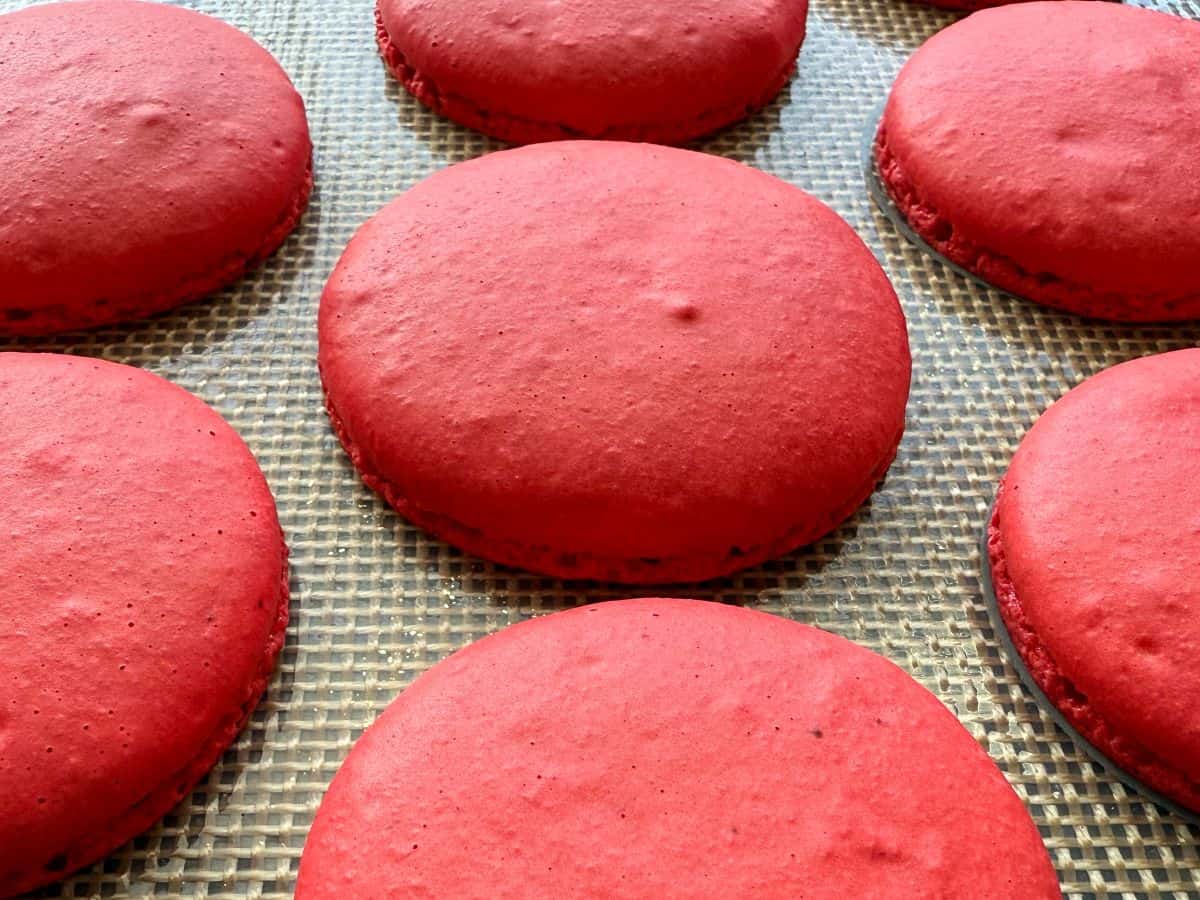 red macaron shells baked on a macaron mat