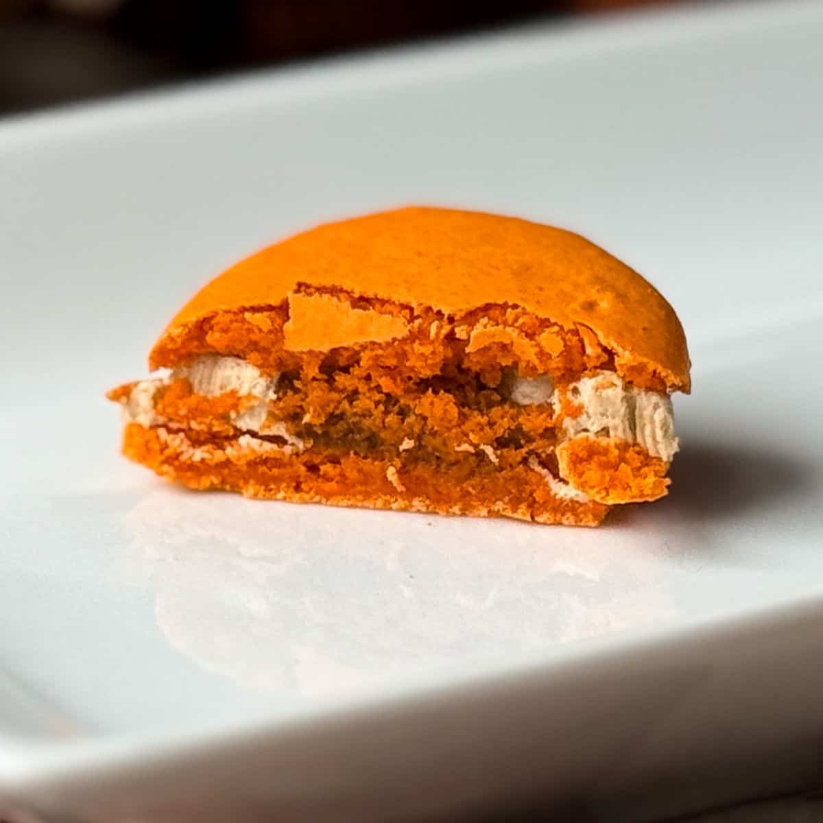 a Nut Free Pumpkin Spice Latte Macaron cut in half to show the filling inside