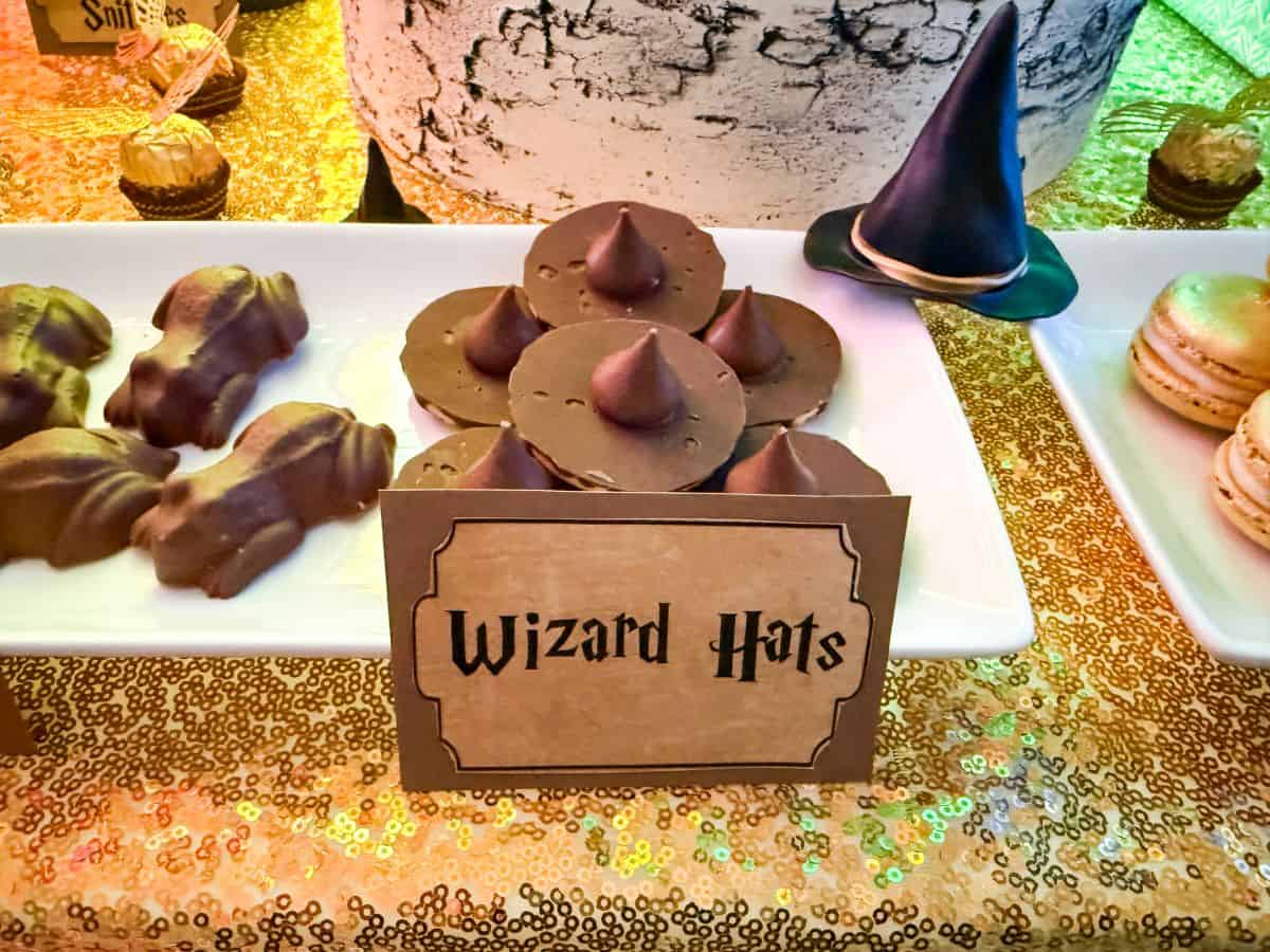 Chocolate Wizard Hat Cookies stacked on a white plate with a "Wizard Hats" food label in front