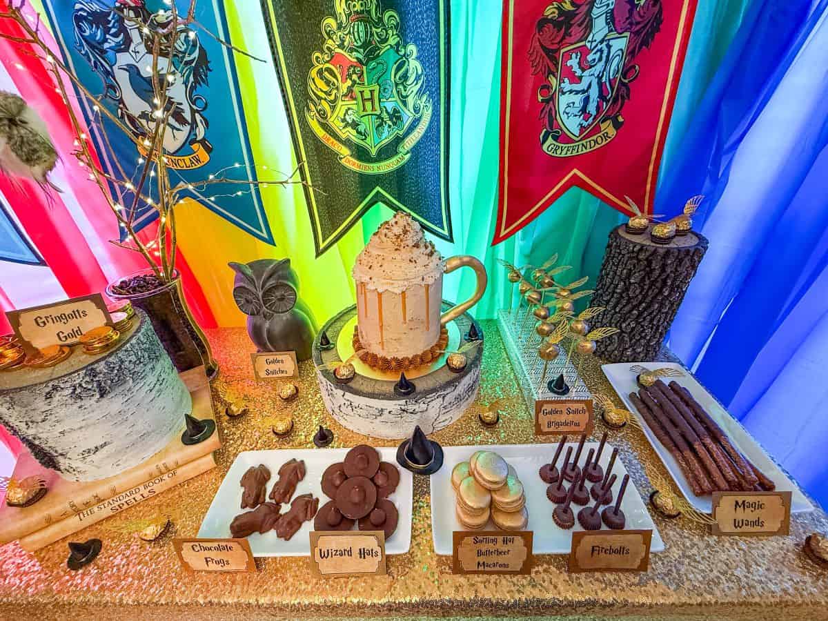 a Harry Potter dessert table showing all of the themed treats and a Butterbeer Cake in the center