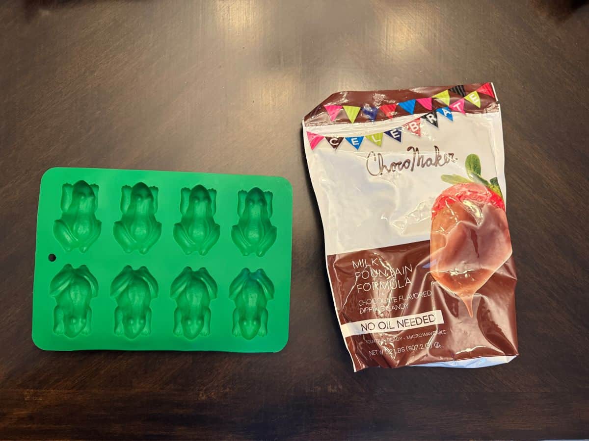 a chocolate frog silicone mold next to a bag of chocolate fountain chocolate