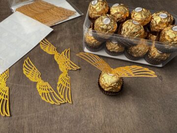 a Ferrero Rocher candy with gold glitter cardstock wings attached to the top