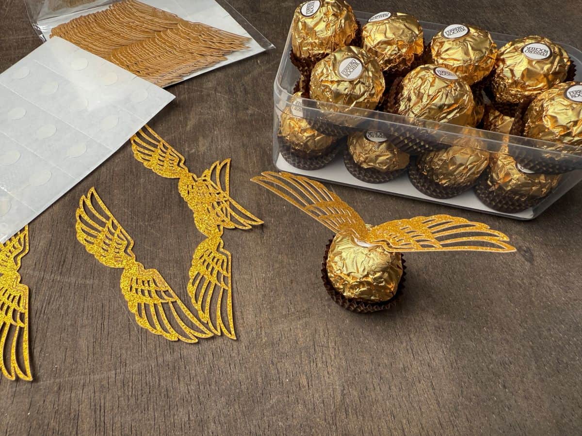 a Ferrero Rocher candy with gold glitter cardstock wings attached to the top