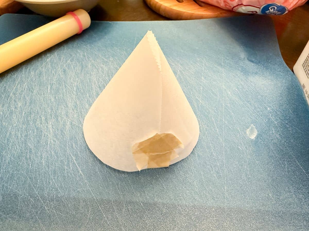 a piece of parchment paper taped into a cone shape on a cutting mat