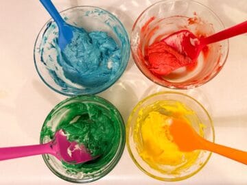 4 cups with colored buttercream in colors blue, red, green and yellow