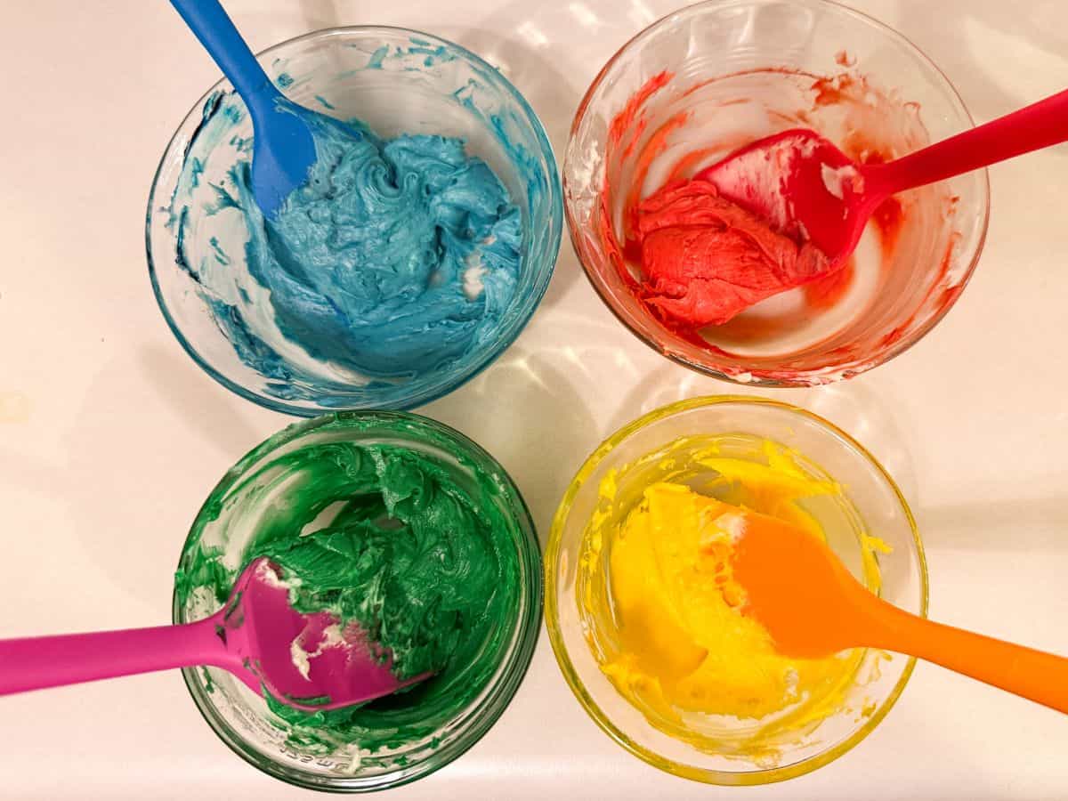 4 cups with colored buttercream in colors blue, red, green and yellow