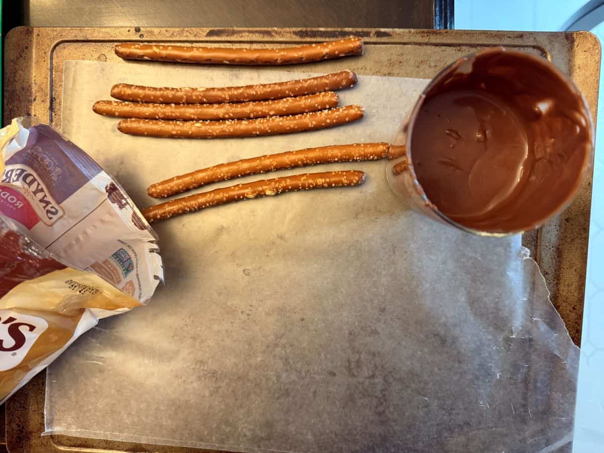 pretzel rods next to a cup of melted chocolate