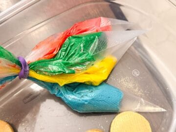 piping bags filled with red, green, yellow and blue buttercream