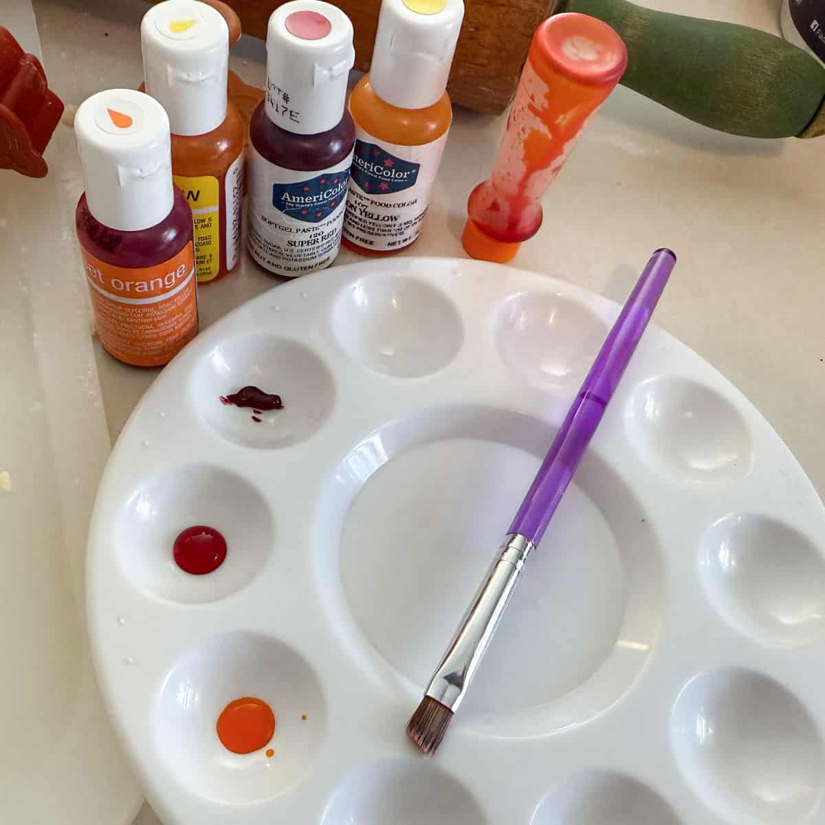a paint palette with fall colors of food coloring gel and a food safe paintbrush