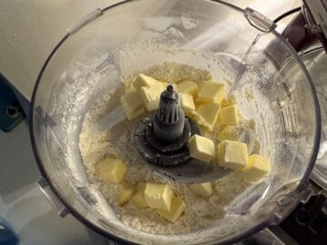 diced butter scattered over dry ingredients in the bowl of a food processor