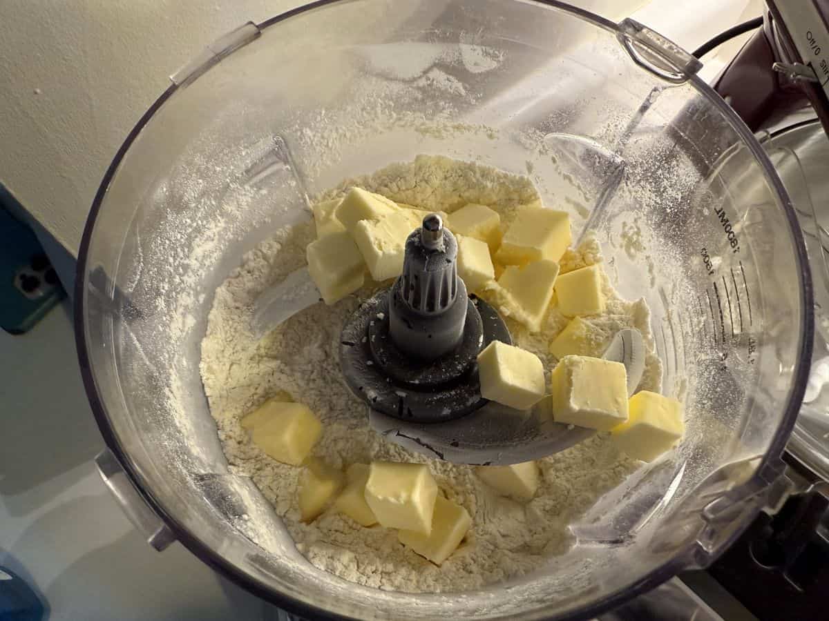 diced butter scattered over dry ingredients in the bowl of a food processor