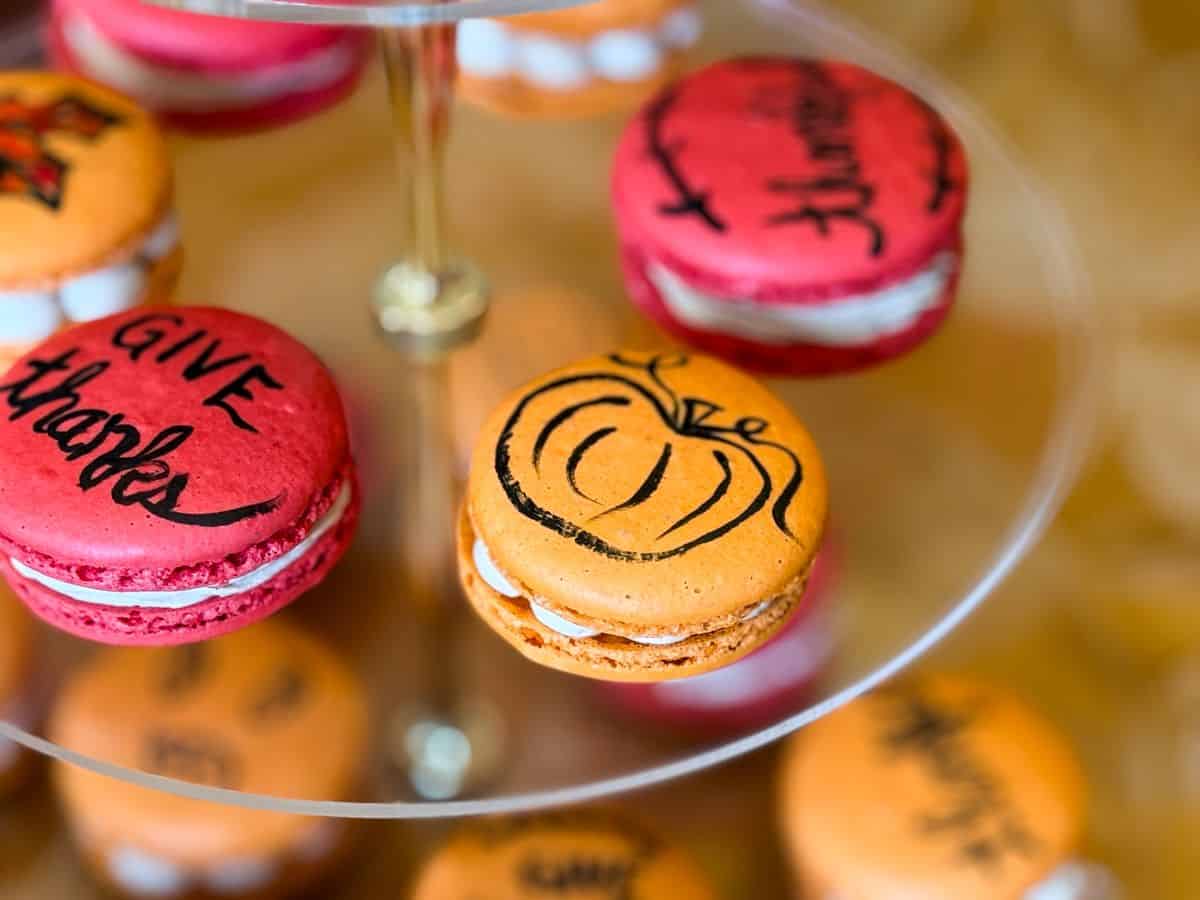 an orange macaron on a 3-tiered server with a black pumpkin outline painted on it