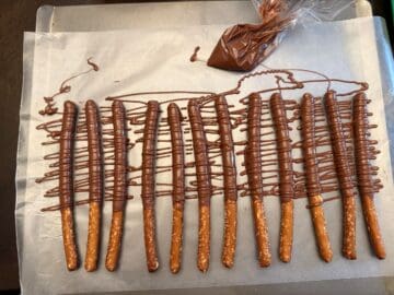 chocolate covered pretzel rods with more chocolate drizzled over them