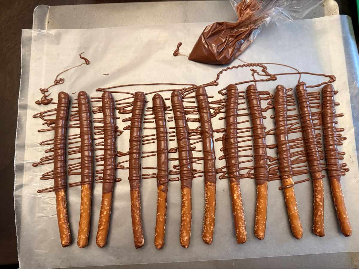 chocolate covered pretzel rods with more chocolate drizzled over them