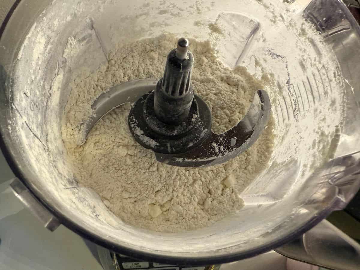 tart shell ingredients being pulsed together in the bowl of a food processor
