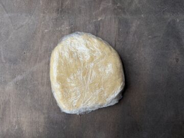 a round disk of tart shell dough wrapped in plastic wrap