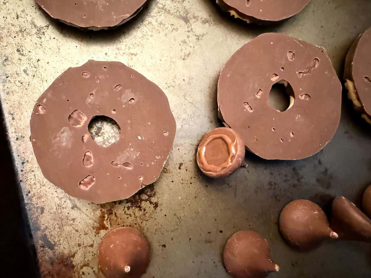 upside down fudge stripe cookies next to an unwrapped Hershey's Kiss with a ring of melted chocolate piped on the bottom