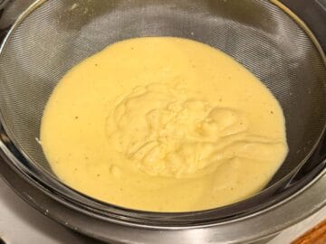 eggnog pastry cream in a fine mesh strainer set over a bowl