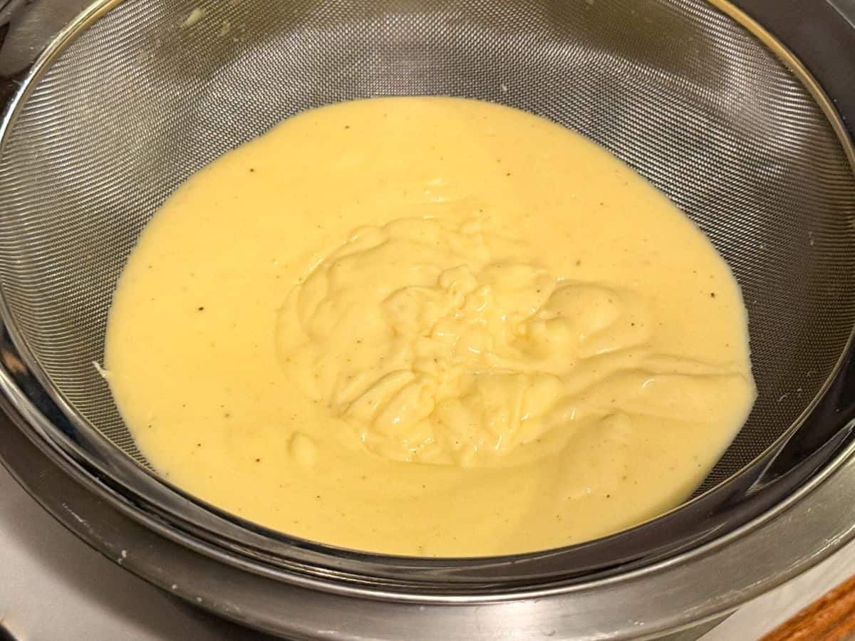 eggnog pastry cream in a fine mesh strainer set over a bowl