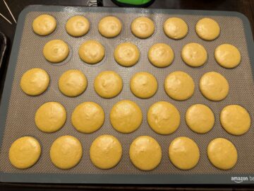 macaron batter piped into 1-inch circles on a macaron mat