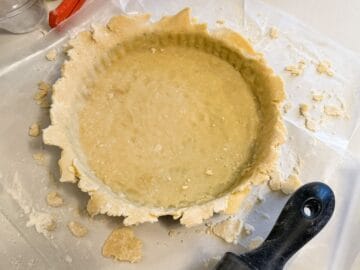 dough fitted into a tart pan but overhanging the edges of the pan