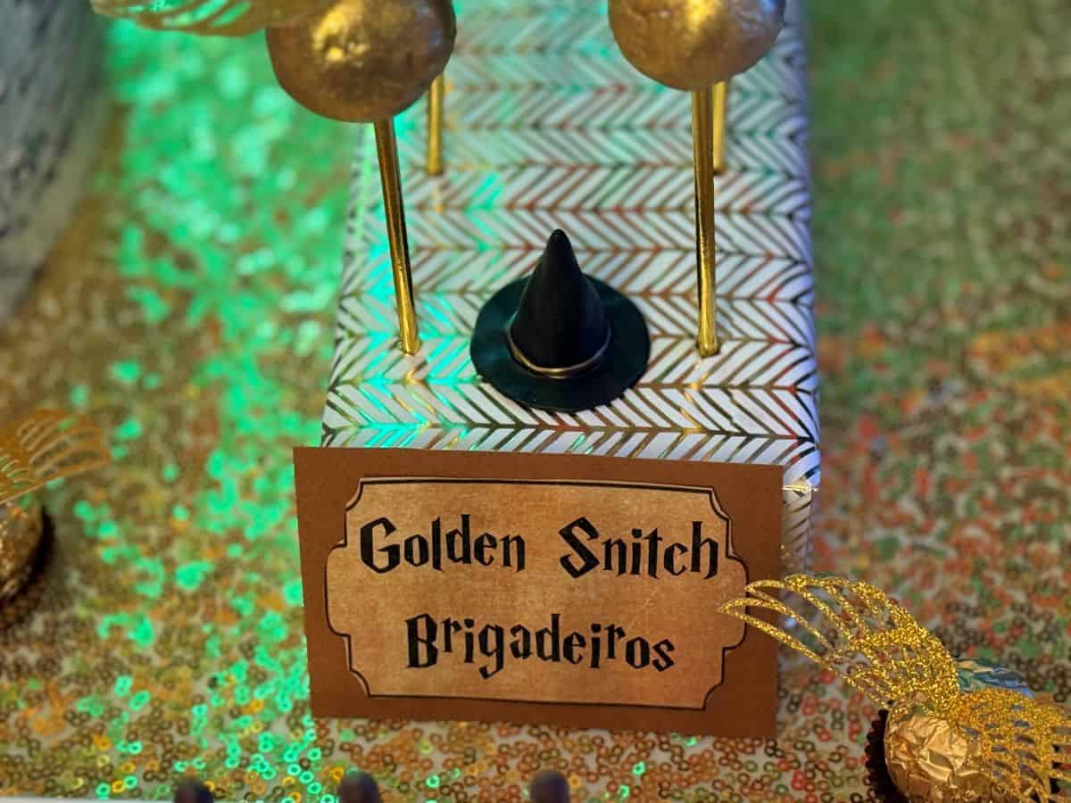 a sign that says "Golden Snitch Brigadeiros" in front of the candies in a display block