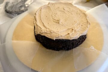 an even layer of butterscotch buttercream smoothed over a single layer of chocolate cake