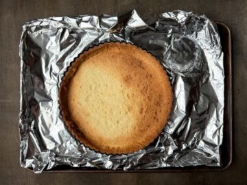 a baked cookie tart shell on a foil lined baking sheet