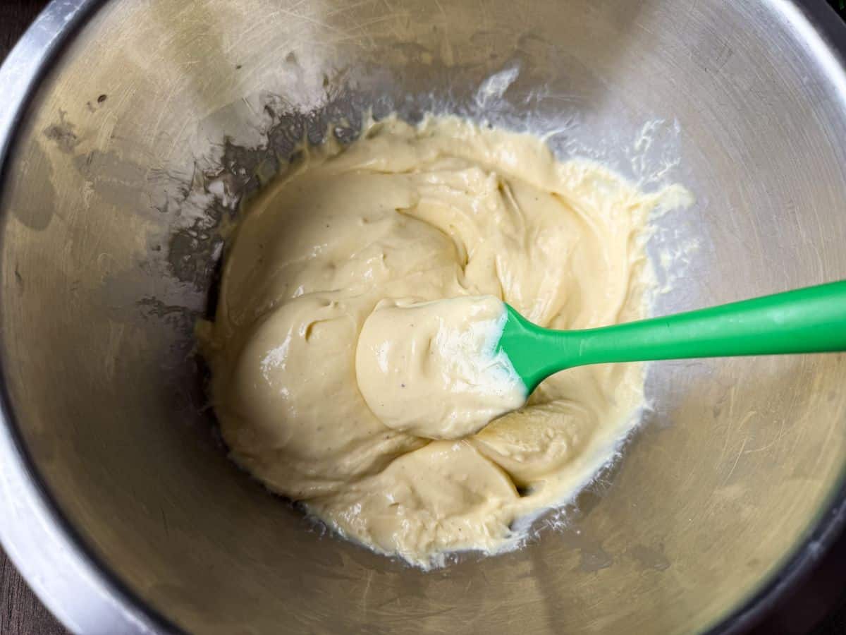 eggnog pastry cream in a metal bowl with a small green silicone spatula
