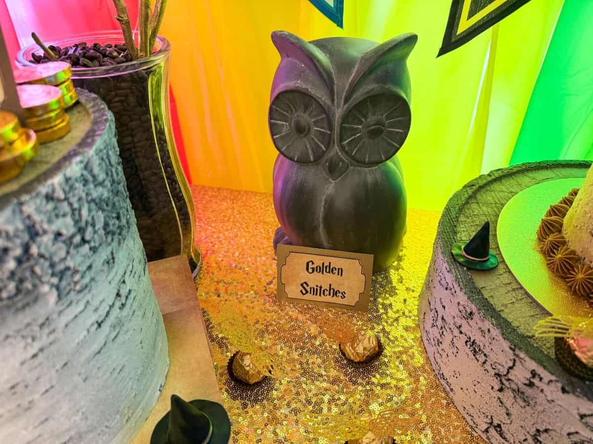 a metal owl with a sign in front that says "Golden Snitches" on a Harry Potter dessert table