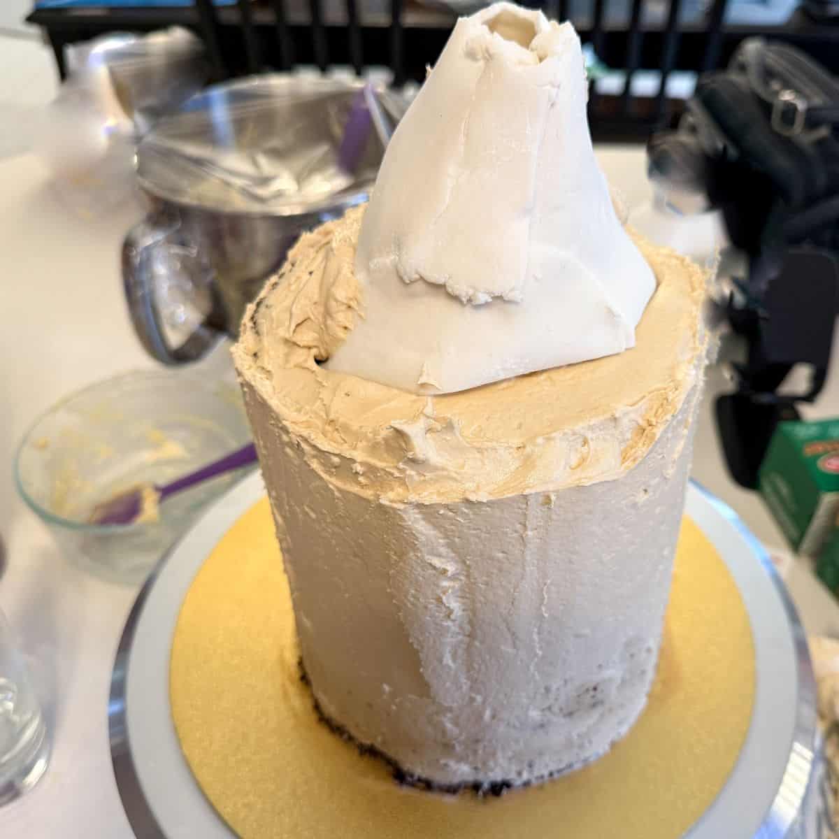 a white fondant cone on top of a butterscotch buttercream covered cake