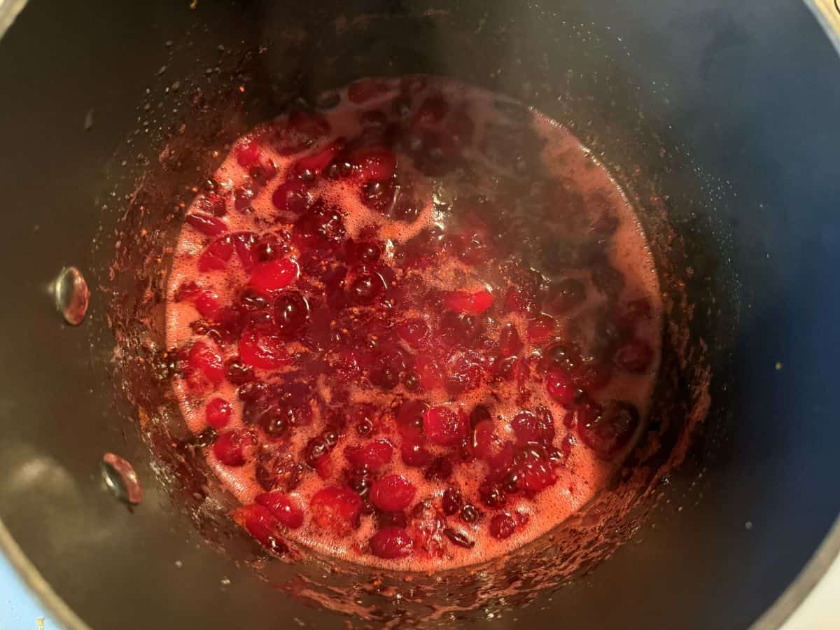 cranberries bursting in a saucepan on the stove