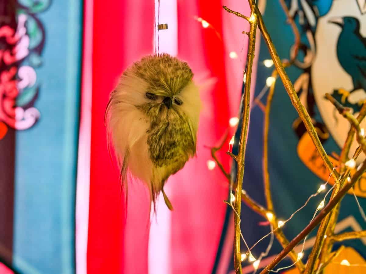 an owl ornament hanging from branches decorated with string lights