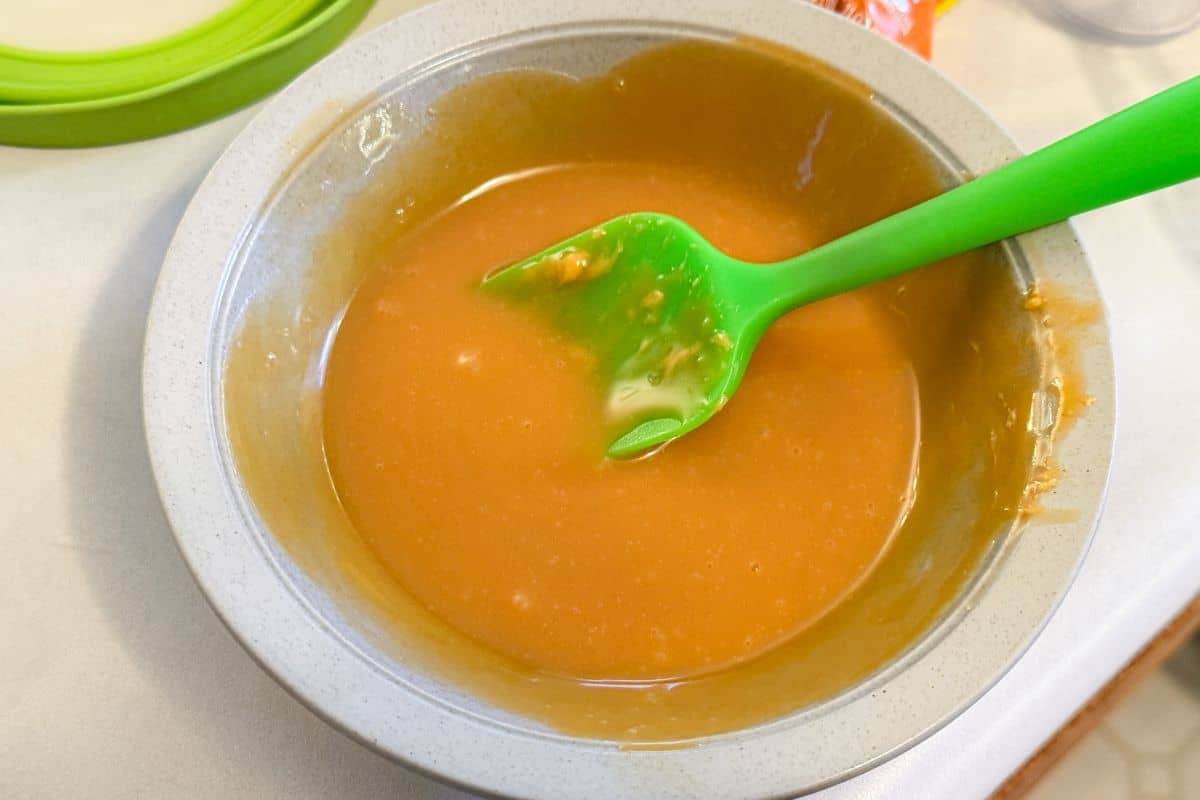 melted butterscotch drips in a bowl with a small green silicone spatula