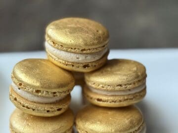 assembled butterbeer macarons stacked on a white plate