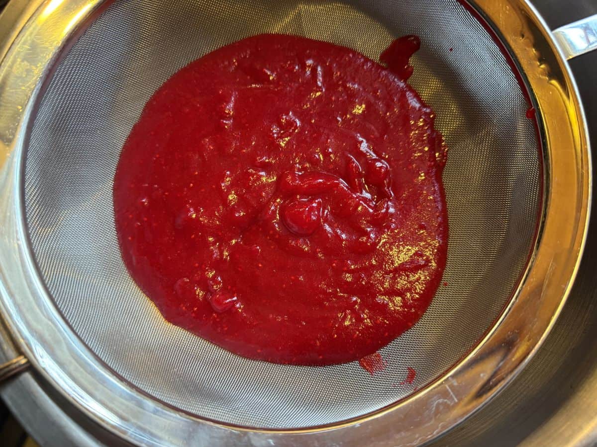 cranberry puree in a fine mesh wire strainer set over a bowl