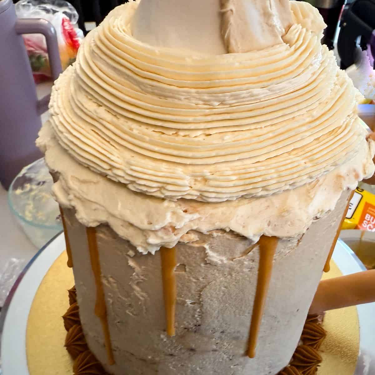 vanilla buttercream piped around a white fondant cone on top of a Butterbeer Cake
