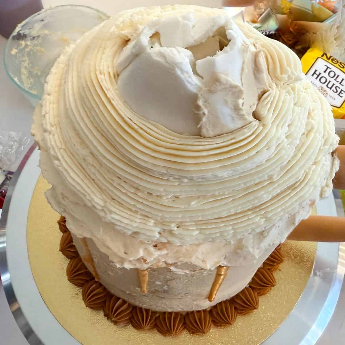 vanilla buttercream piped around a white fondant cone on top of a Butterbeer Cake