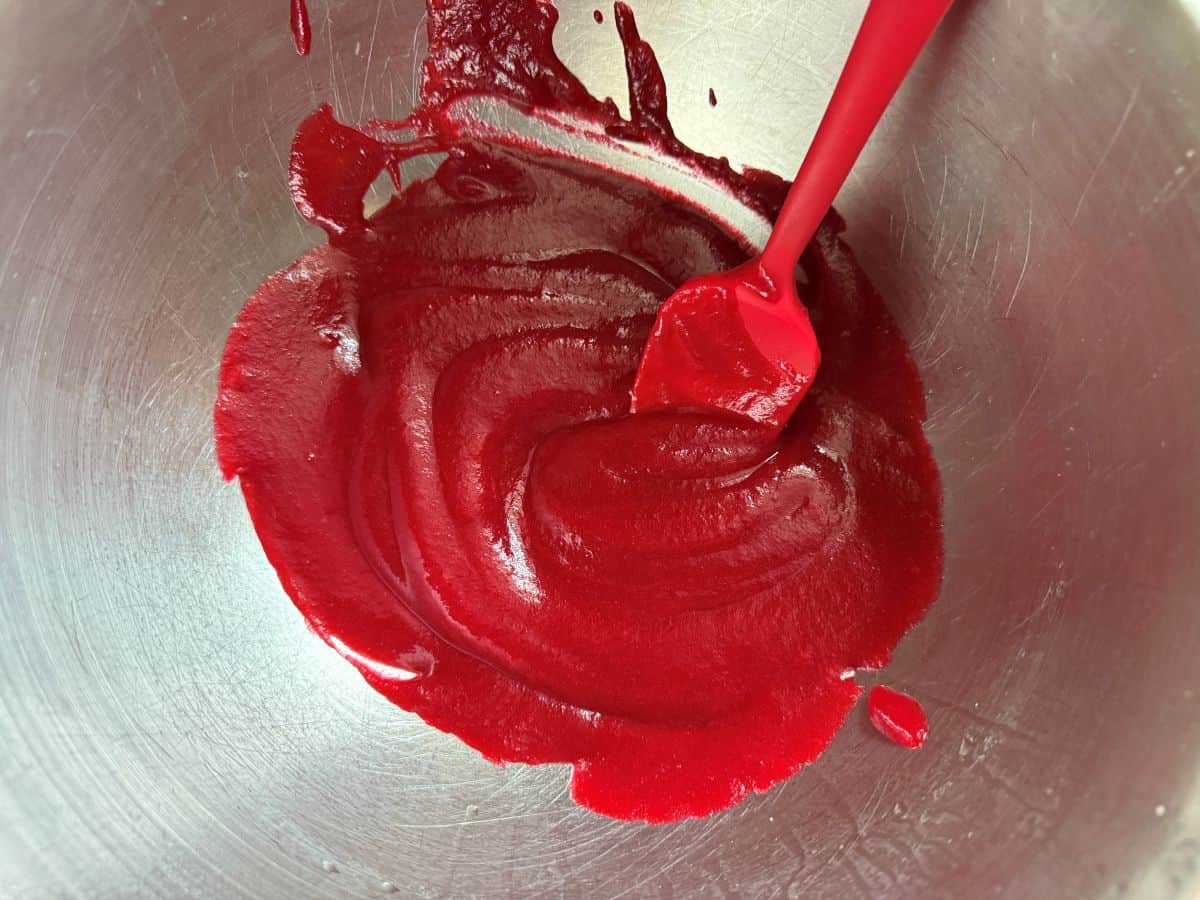 strained cranberry puree in a bowl with a small silicone whisk