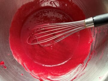 strained cranberry puree whisked with egg mixture in a bowl with a wire whisk