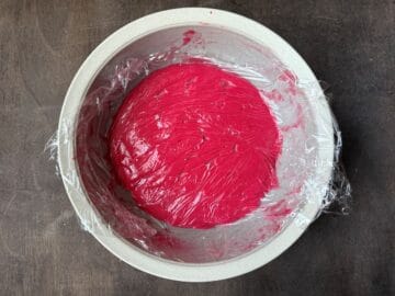 plastic wrap pressed on the surface of cranberry curd in a bowl