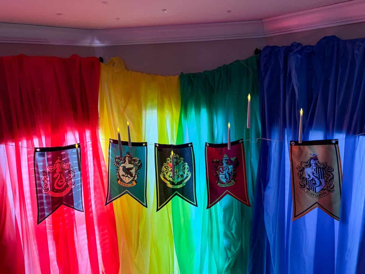 floating candles hanging from a kitchen ceiling with red, yellow, green and blue panels and Hogwarts house banners