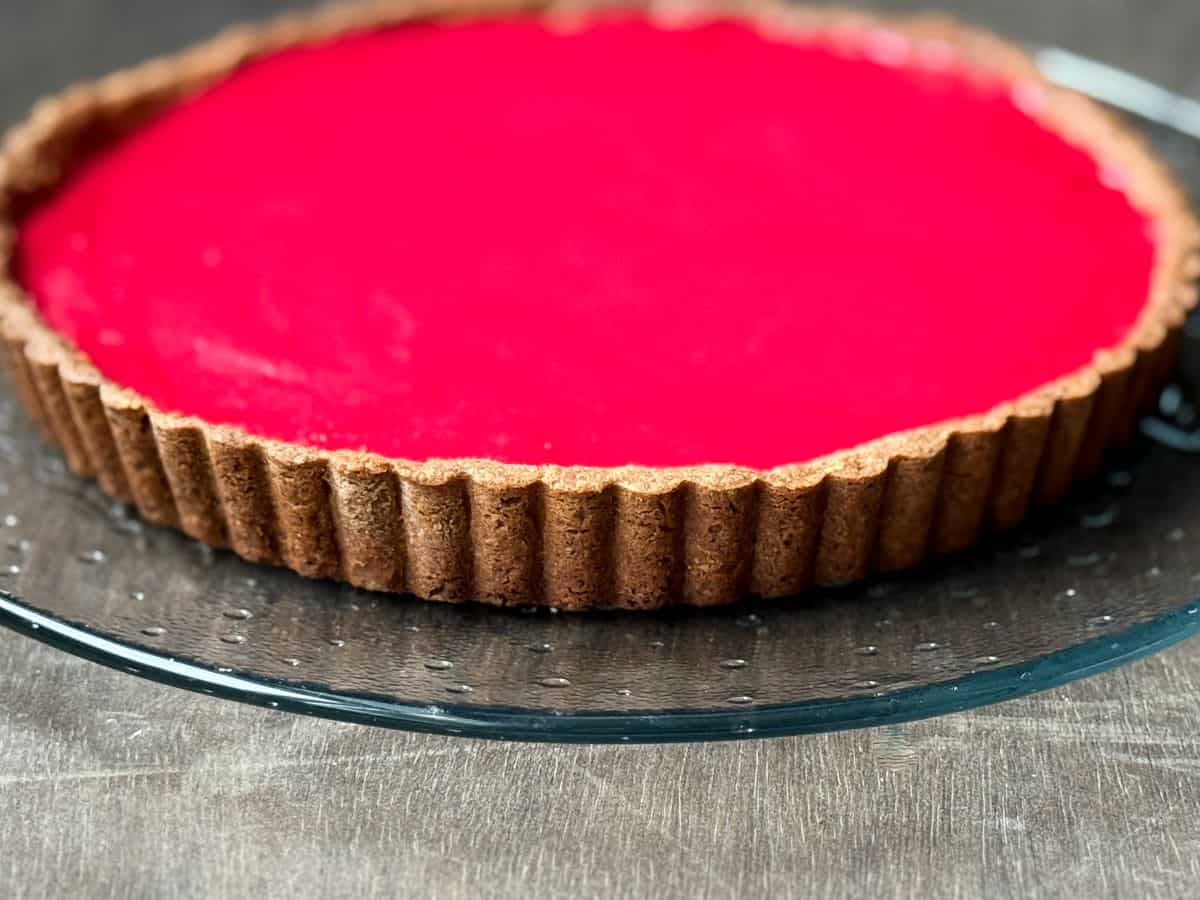 the side of a cranberry curd tart showing the golden brown crust