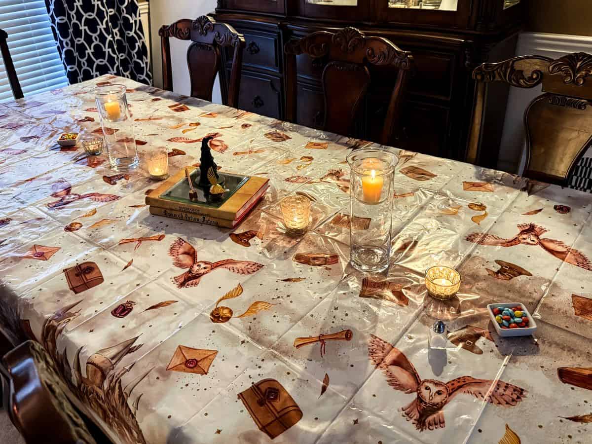 dining room table with a Harry Potter tablecloth and centerpieces running down the middle of the table
