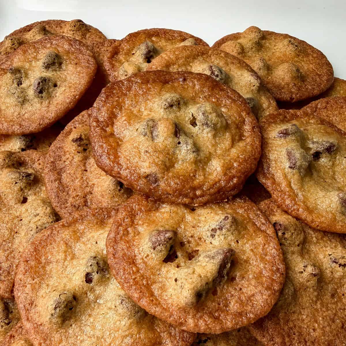 a stack of the Crispiest Chocolate Chip Cookies on a white plate